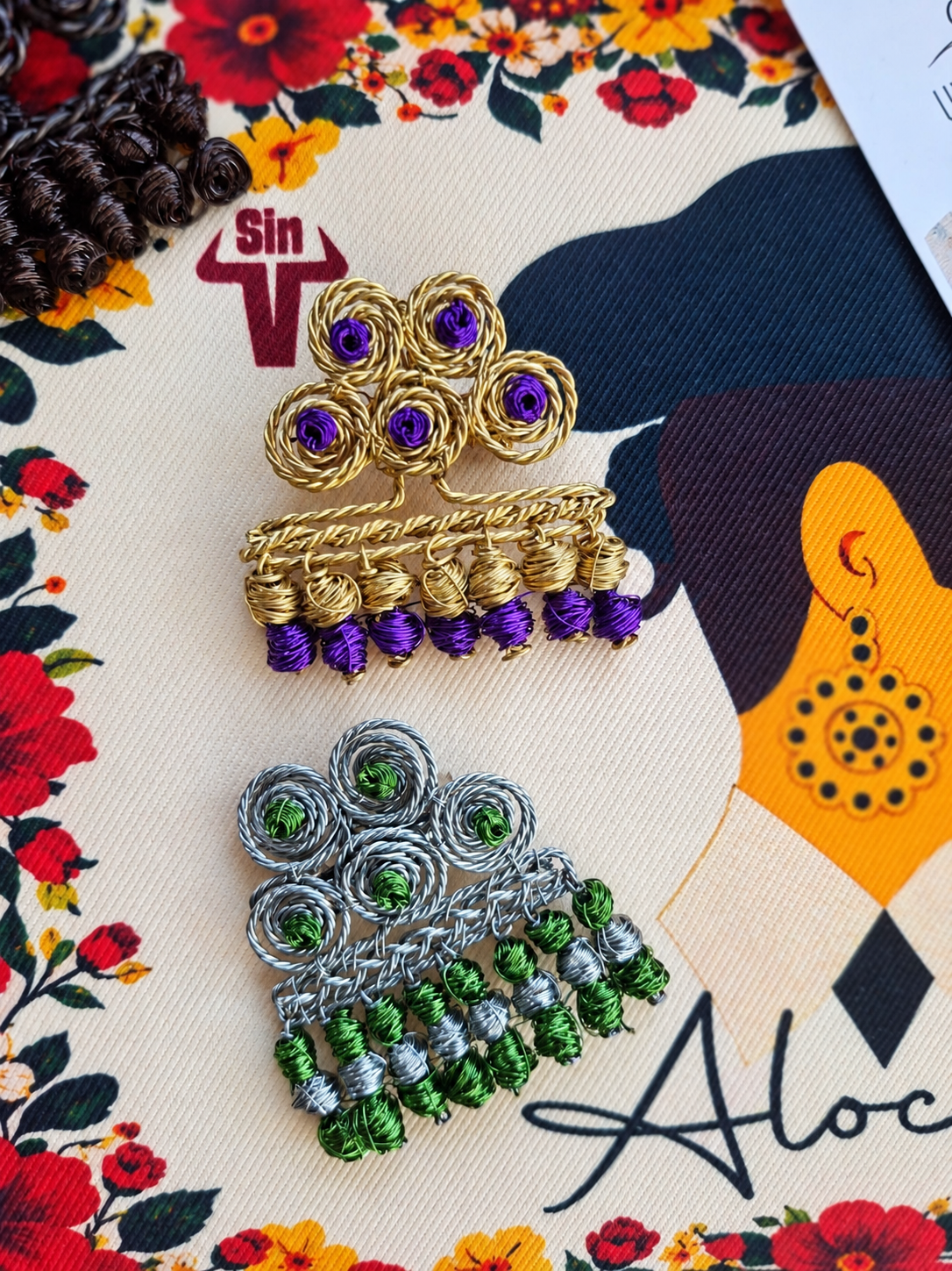 Broche de alambre plateado con cuentas verdes y dorado con cuentas moradas, Una de Belén