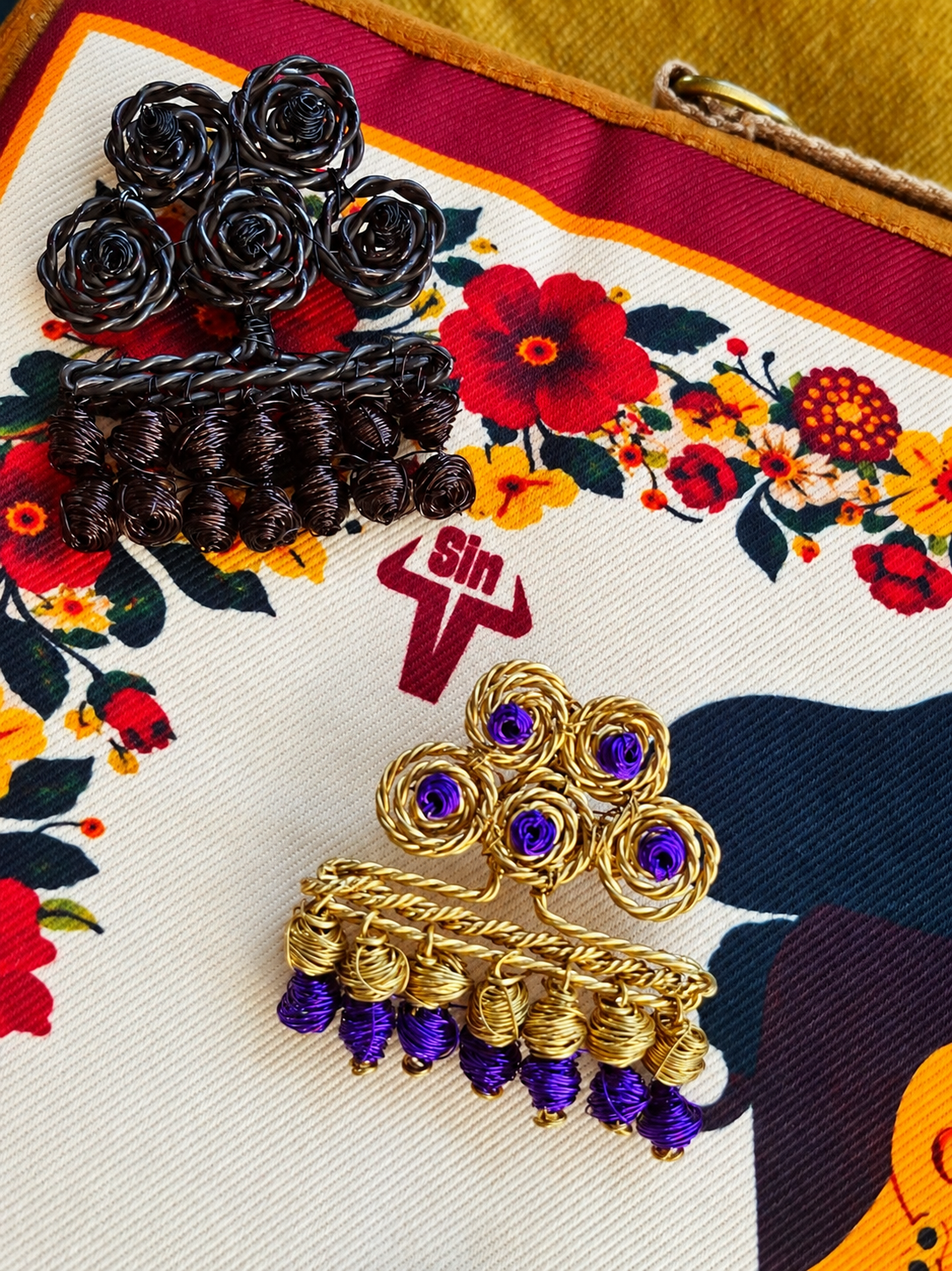 Broche de alambre dorado con cuentas moradas y broche bronce, Una de Belén