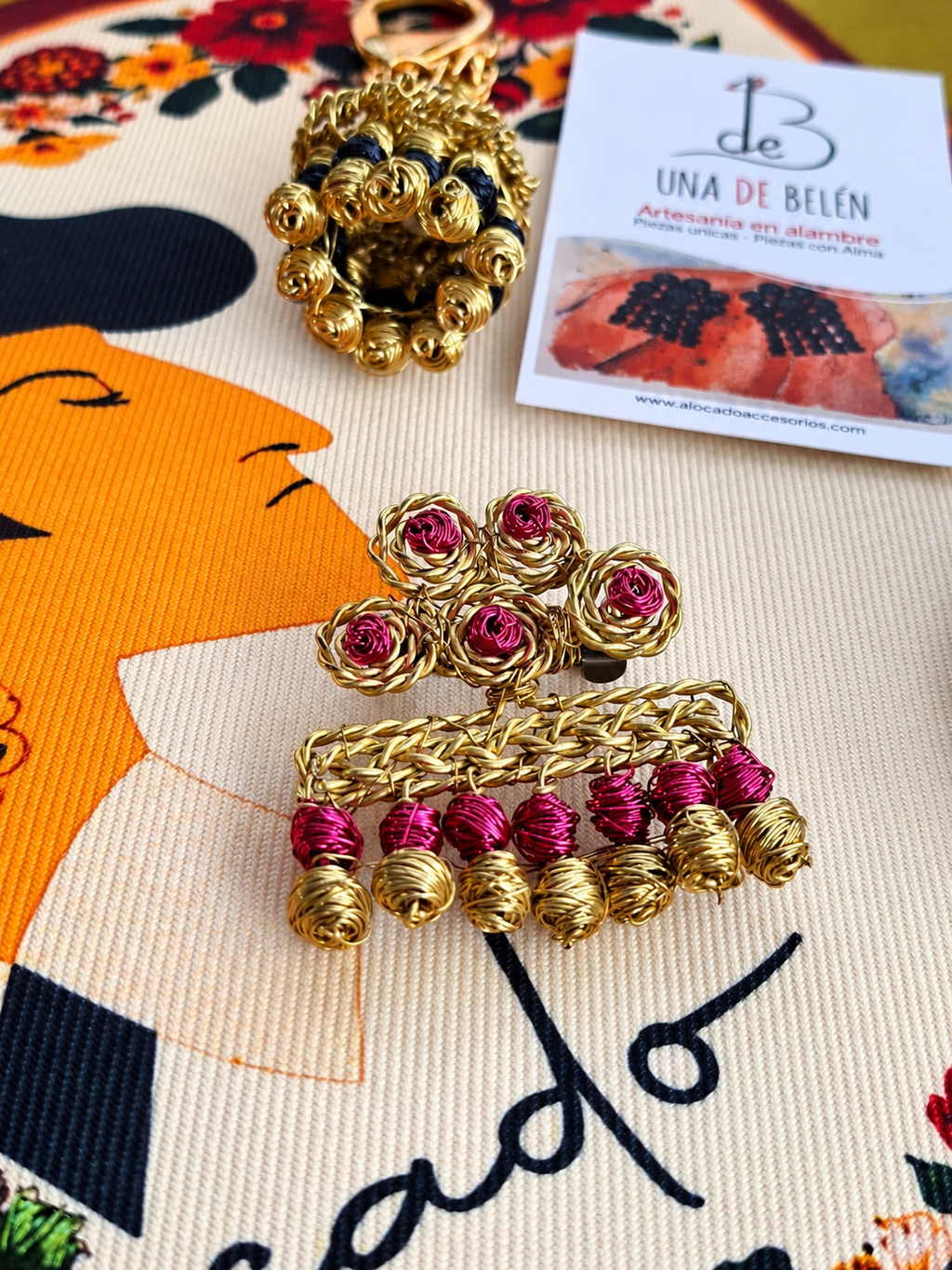 Broche de alambre dorado con cuentas fucsia y llavero dorado y negro, Una de Belén