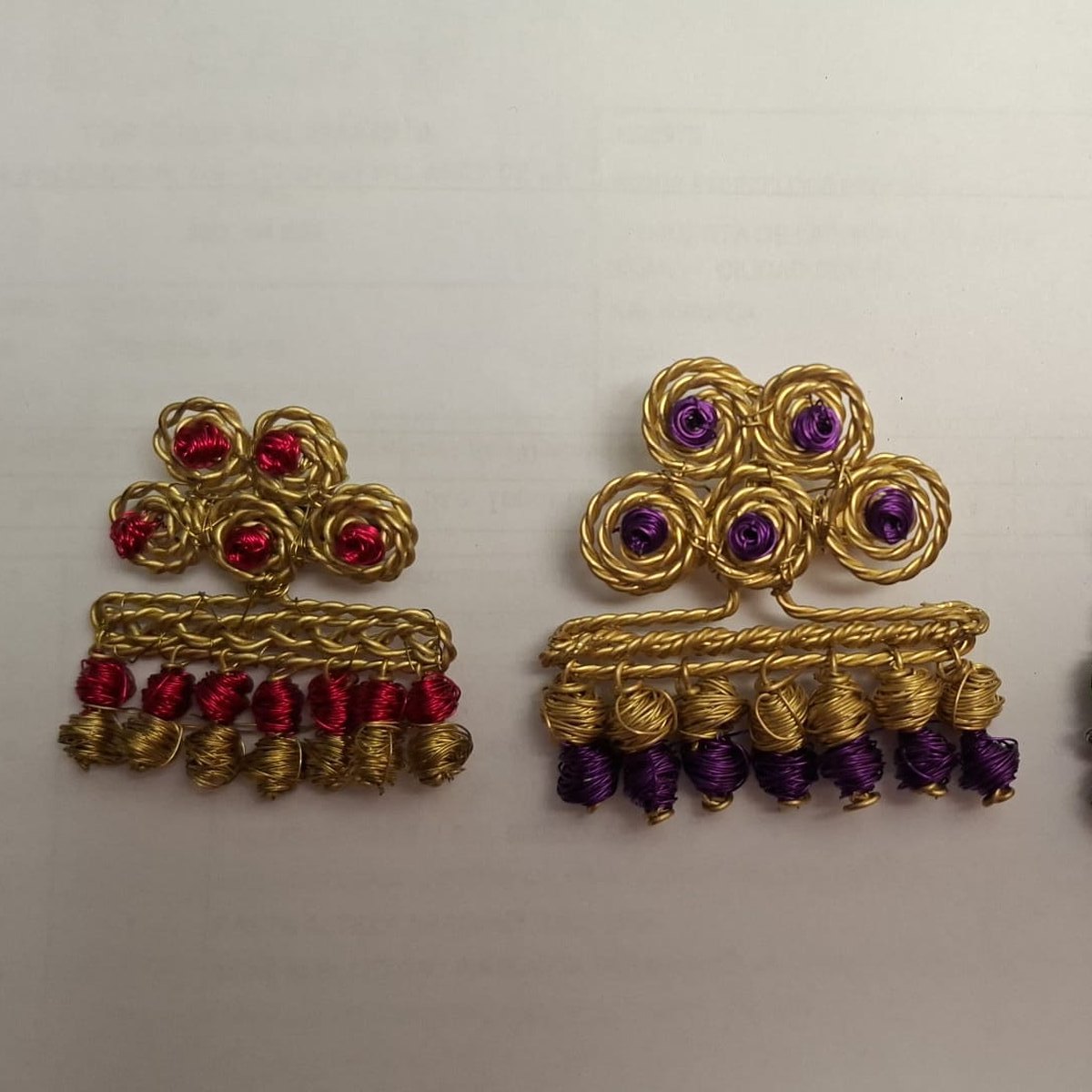 Broches de alambre dorado con cuentas rojas y moradas, Una de Belén